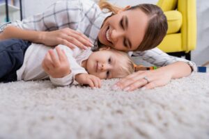 Mother and baby lying on carpet