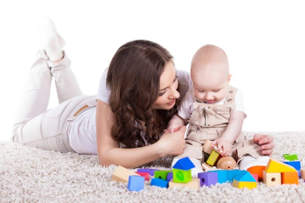 Mother with baby playing with blocks on a rug